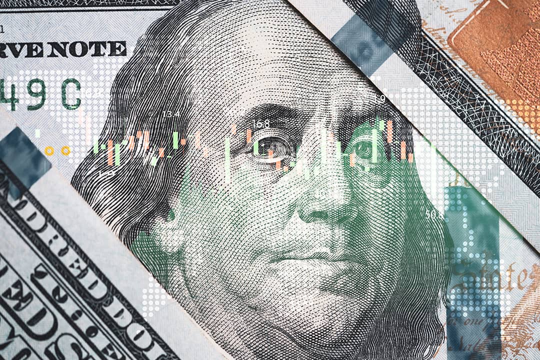 A close-up of Benjamin Franklin's face on a U.S. 100-dollar bill overlaid with a stock market trading chart.